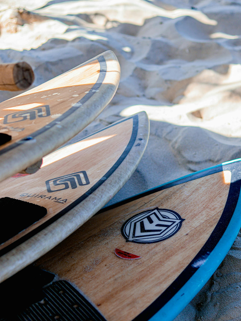 Close-up of wooden surfboards with branding on a sandy background